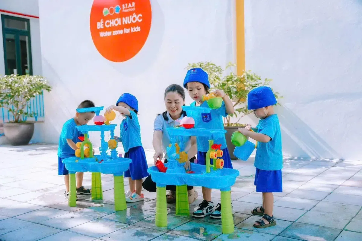 Các bé chơi với nước ở khu vực ngoài trời
